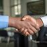 Two people shaking hands across a desk, representing a B2B supplier shortlist decision