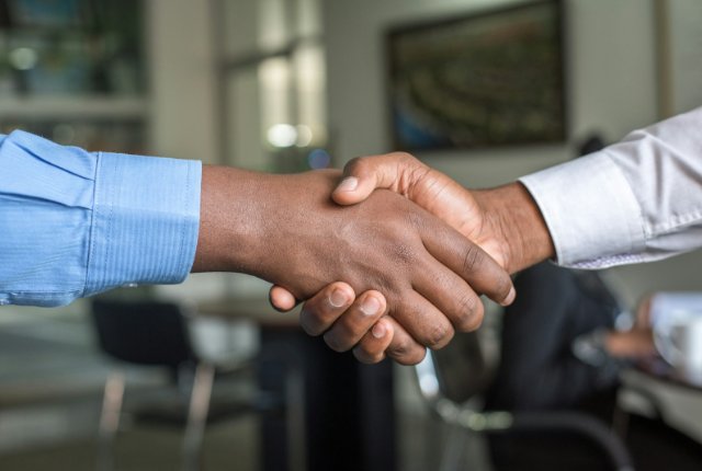 Two people shaking hands across a desk, representing a B2B supplier shortlist decision