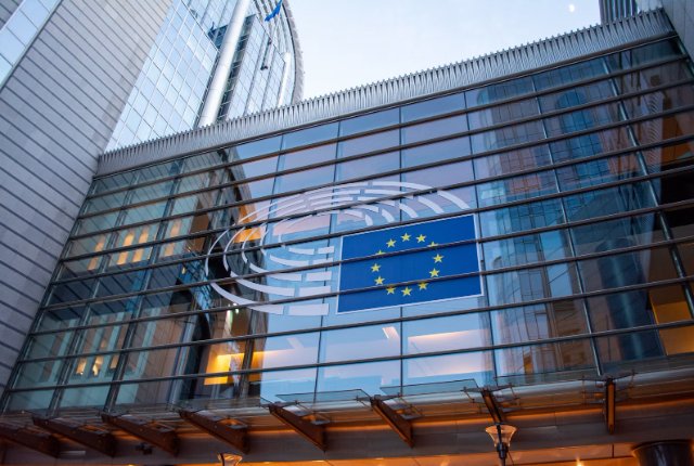 European Union flag reflected in a modern glass building