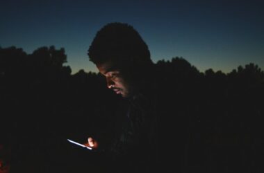 A person using a smartphone in the dark, representing late night social media use by teenagers