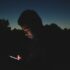 A person using a smartphone in the dark, representing late night social media use by teenagers